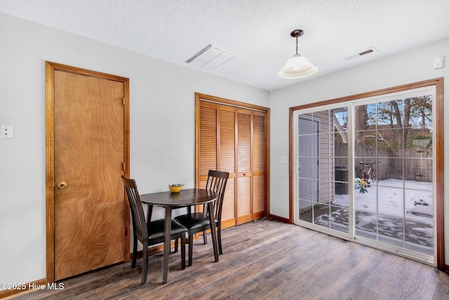 dining space with dark wood-type flooring and a textured ceiling