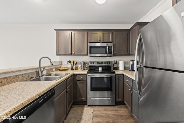 kitchen featuring appliances with stainless steel finishes, dark hardwood / wood-style floors, sink, dark brown cabinetry, and crown molding