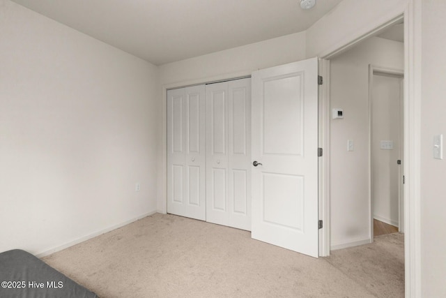 unfurnished bedroom with light colored carpet and a closet