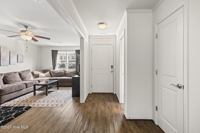 foyer with dark wood-type flooring, ceiling fan, and ornamental molding