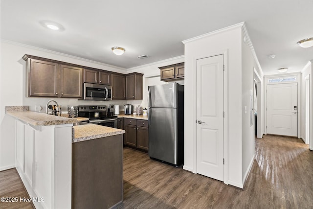 kitchen with appliances with stainless steel finishes, dark brown cabinets, ornamental molding, dark hardwood / wood-style flooring, and kitchen peninsula