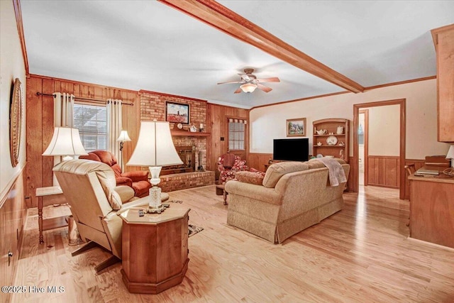 living room with crown molding, beam ceiling, a brick fireplace, built in shelves, and light wood-type flooring