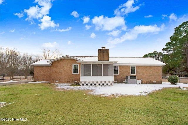 back of property with central AC unit, a sunroom, and a lawn