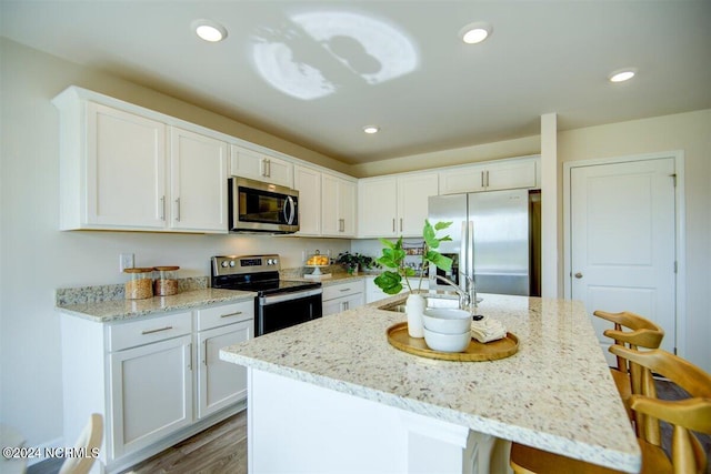 kitchen with stainless steel appliances, a sink, white cabinetry, and recessed lighting