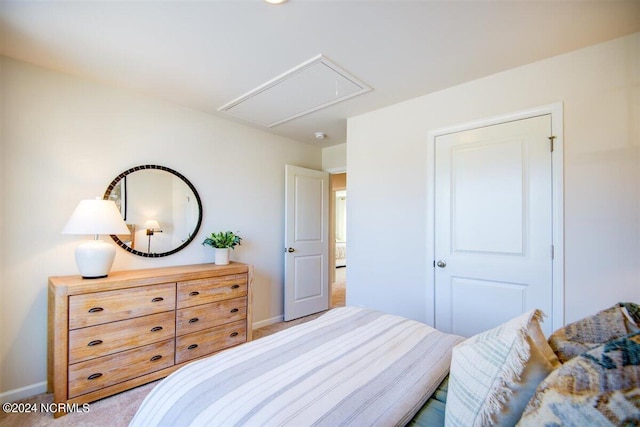 bedroom with attic access, light carpet, and baseboards