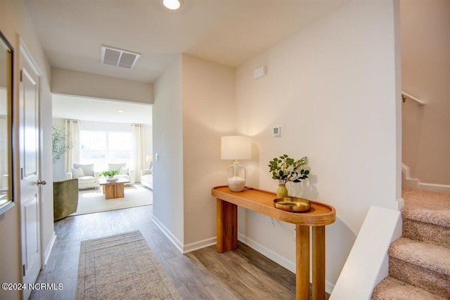 hall featuring stairway, baseboards, visible vents, and wood finished floors