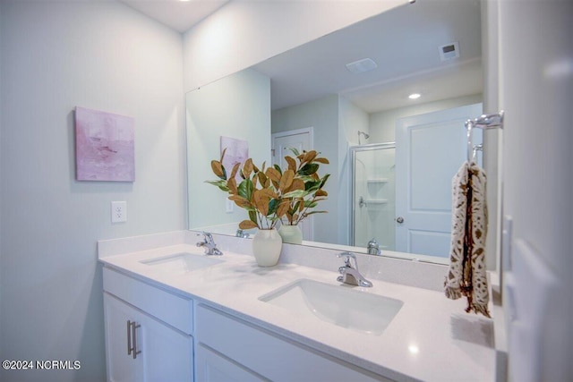 bathroom featuring double vanity, a stall shower, visible vents, and a sink