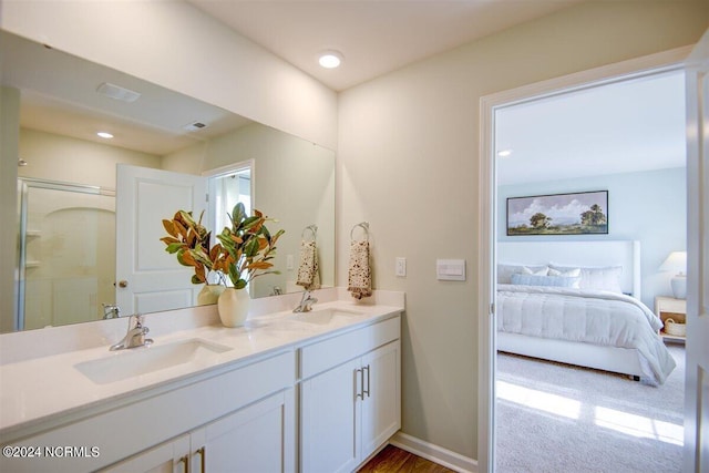 ensuite bathroom featuring connected bathroom, a sink, baseboards, and double vanity