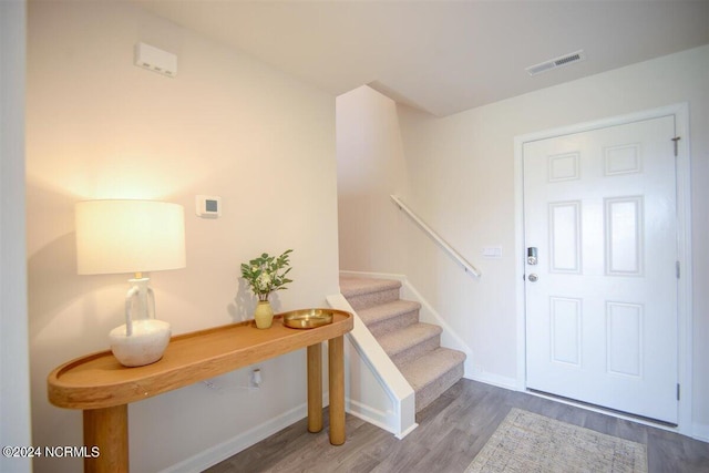 foyer entrance featuring wood finished floors, visible vents, baseboards, and stairs