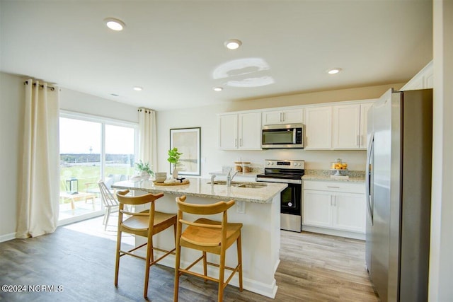 kitchen featuring light stone counters, appliances with stainless steel finishes, a sink, and white cabinetry