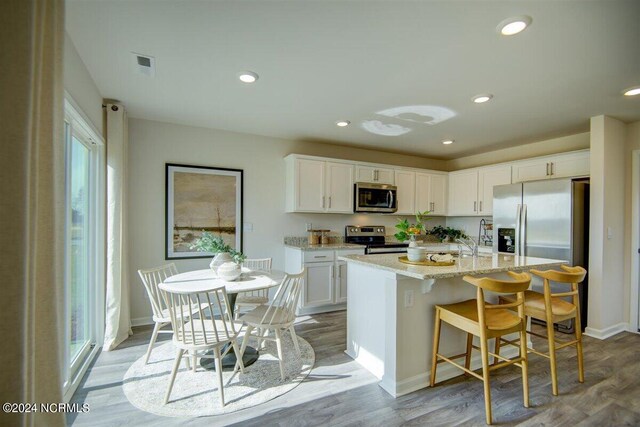 kitchen featuring a kitchen island with sink, sink, stainless steel appliances, and white cabinets