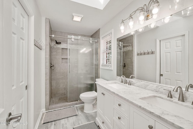 bathroom featuring an enclosed shower, vanity, a skylight, and hardwood / wood-style floors