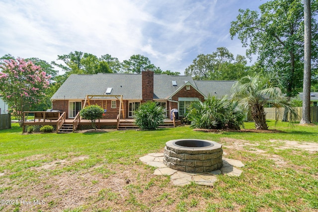 rear view of property with a wooden deck, an outdoor fire pit, and a lawn