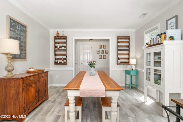 dining room featuring crown molding and light hardwood / wood-style floors