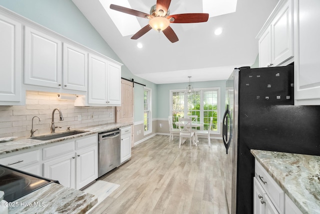 kitchen with lofted ceiling, sink, white cabinetry, light wood-type flooring, and stainless steel appliances