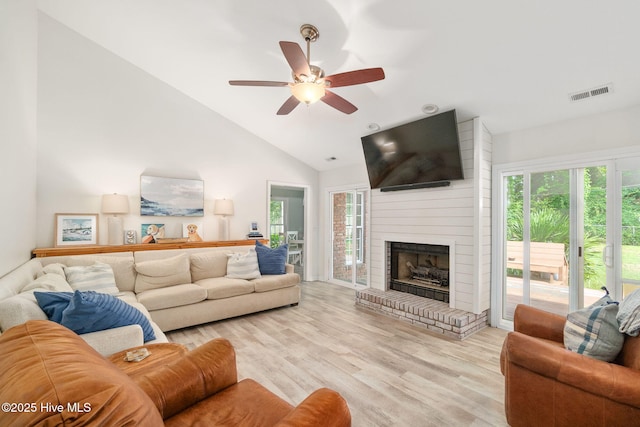 living room featuring ceiling fan, a healthy amount of sunlight, a fireplace, and light wood-type flooring