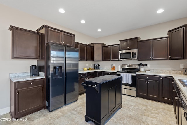 kitchen with dark brown cabinetry, appliances with stainless steel finishes, light stone countertops, and a kitchen island