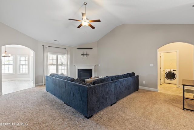 living room with ceiling fan, light colored carpet, washer / dryer, and vaulted ceiling