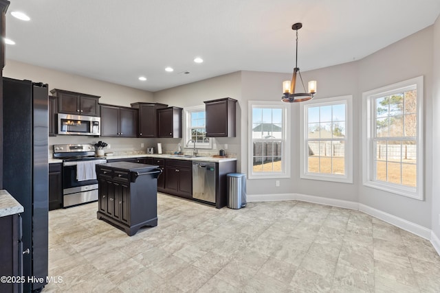 kitchen featuring pendant lighting, sink, appliances with stainless steel finishes, dark brown cabinetry, and a kitchen island