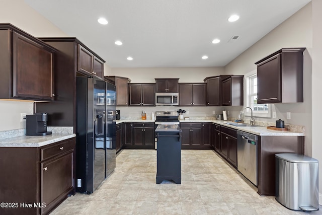 kitchen with dark brown cabinetry, appliances with stainless steel finishes, a center island, and sink