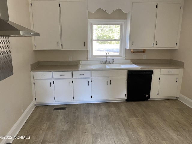 kitchen with white cabinetry, black dishwasher, light hardwood / wood-style flooring, and wall chimney range hood