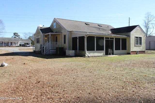 rear view of property with a sunroom and a yard