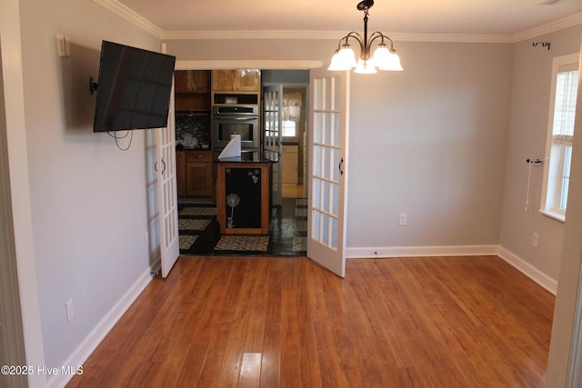 interior space with a notable chandelier, crown molding, wood-type flooring, and french doors