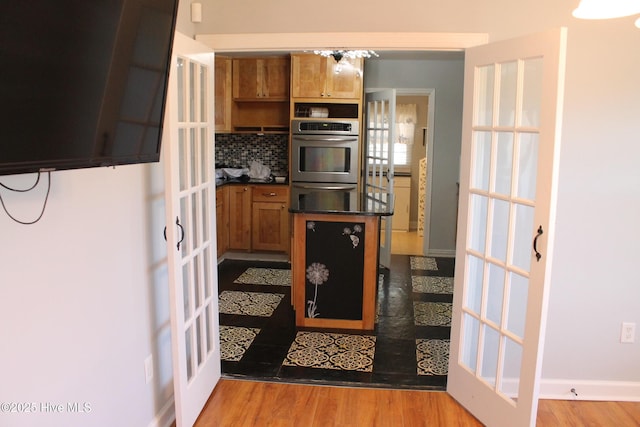 kitchen with french doors, double oven, tasteful backsplash, and light wood-type flooring