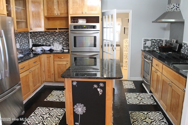 kitchen with stainless steel appliances, a center island, dark stone counters, and wall chimney exhaust hood