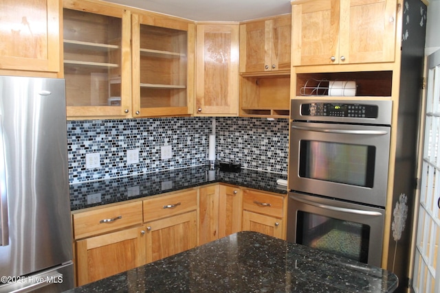 kitchen with tasteful backsplash, appliances with stainless steel finishes, and dark stone countertops