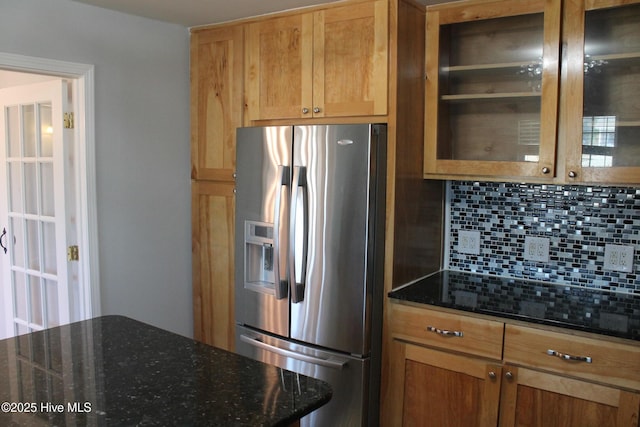 kitchen with stainless steel fridge with ice dispenser, backsplash, and dark stone counters