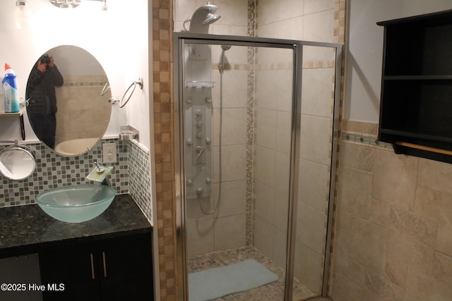 bathroom featuring vanity, backsplash, and a shower with door