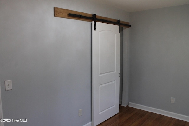 empty room featuring a barn door and dark hardwood / wood-style flooring