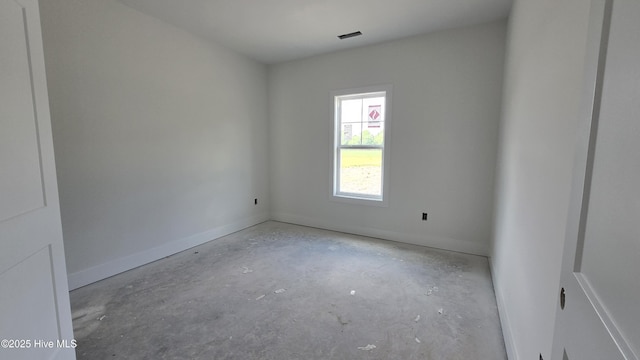 spare room with unfinished concrete floors, baseboards, and visible vents