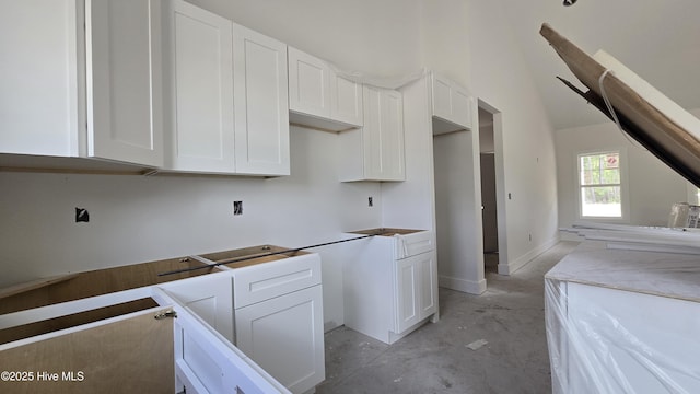 kitchen featuring concrete floors and white cabinetry