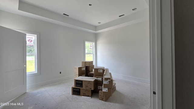 miscellaneous room with visible vents, baseboards, a raised ceiling, and unfinished concrete floors