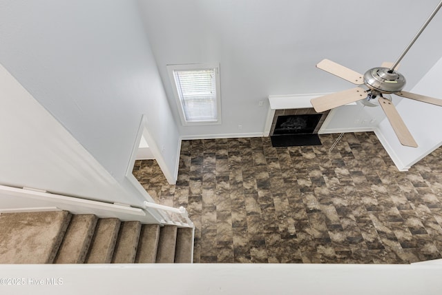 unfurnished living room featuring a tiled fireplace and a ceiling fan