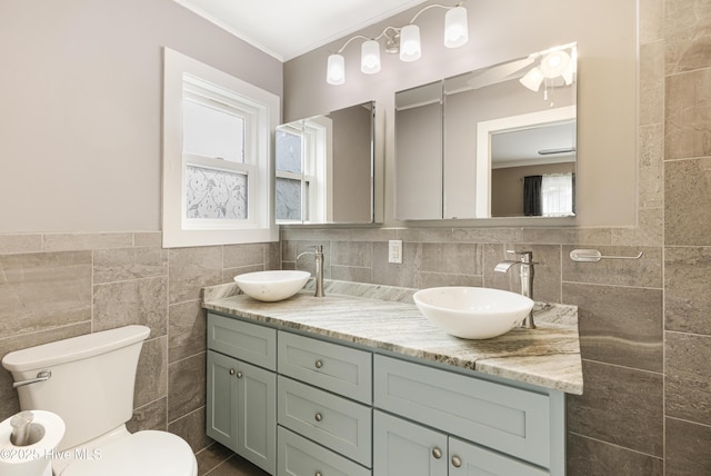 bathroom featuring tile walls, toilet, double vanity, and a sink