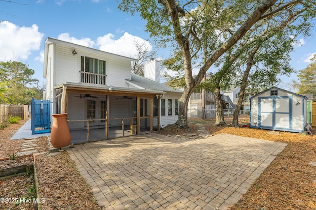 rear view of house featuring a storage shed, a sunroom, ceiling fan, and a patio area