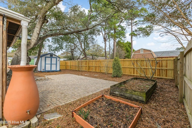 view of yard featuring a patio area, an outbuilding, a fenced backyard, a storage shed, and a vegetable garden
