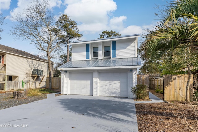 view of front facade with concrete driveway, fence, metal roof, and an attached garage