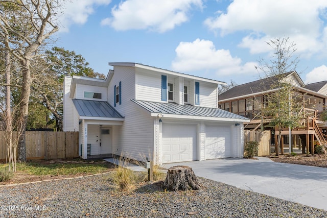 traditional-style home with driveway, a standing seam roof, metal roof, an attached garage, and fence