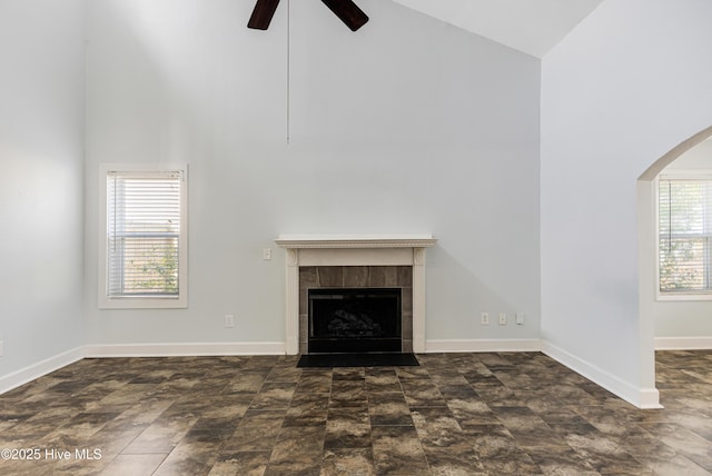 unfurnished living room with a tile fireplace, ceiling fan, and high vaulted ceiling