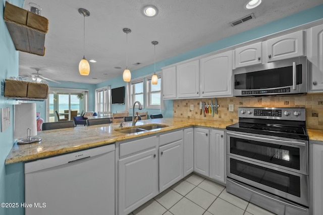 kitchen with sink, decorative light fixtures, kitchen peninsula, stainless steel appliances, and white cabinets