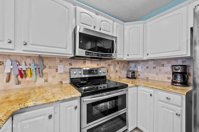 kitchen featuring appliances with stainless steel finishes, tasteful backsplash, white cabinets, light stone counters, and a textured ceiling