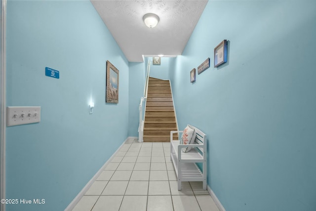 hallway featuring light tile patterned floors and a textured ceiling