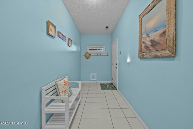 corridor with light tile patterned flooring and a textured ceiling