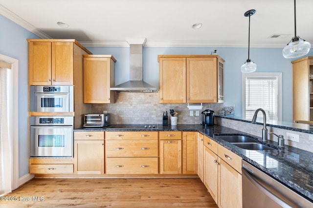 kitchen with appliances with stainless steel finishes, pendant lighting, light brown cabinetry, sink, and wall chimney range hood