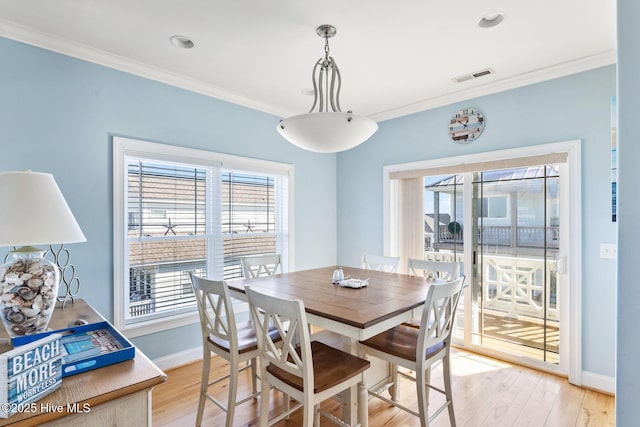 dining area with crown molding and light wood-type flooring