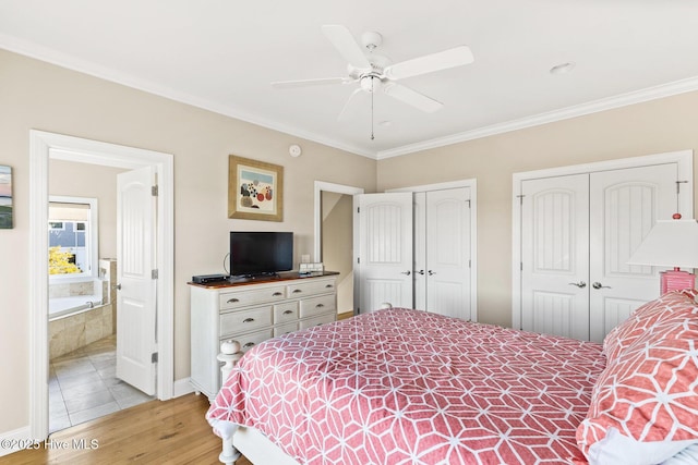 bedroom featuring two closets, ornamental molding, ceiling fan, ensuite bath, and light hardwood / wood-style flooring